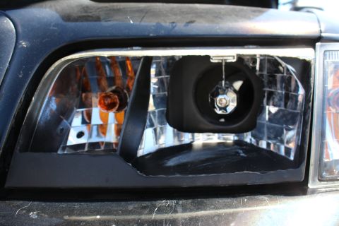 2003 Ford Crown Victoria - Close-up of an open headlight assembly showing the amber turn-signal bulb and an empty chrome bulb socket inside the reflector.
