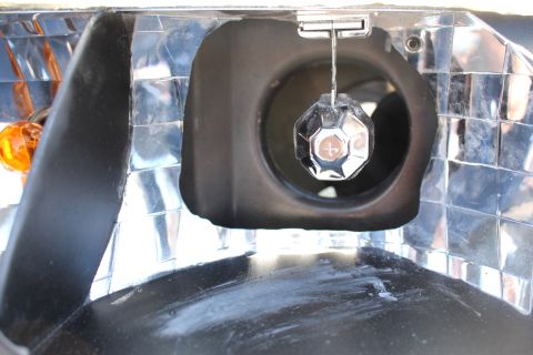 2003 Ford Crown Victoria - extreme close-up inside a headlight housing showing the chrome bulb socket and reflector with the amber turn-signal bulb at left.