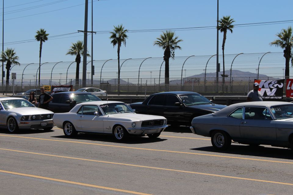 Classic and modern cars staged on track pit lane with palm trees and K&N banner