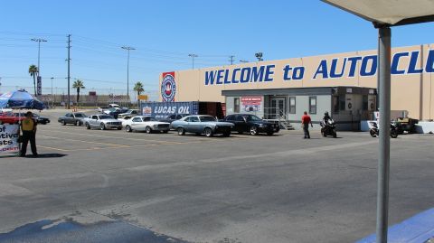 2003 Ford Crown Victoria - Cars and a motorcycle gather near a tan building marked 'WELCOME to AUTO CLUB' with a Lucas Oil banner on a sunny day.