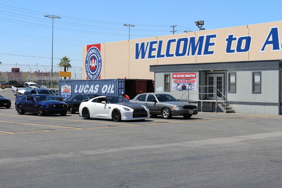 White Nissan GT-R, blue Mustang and sedan parked by Lucas Oil container