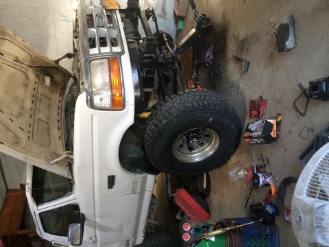 1994 Ford Bronco - White Ford Bronco front end with hood open, parked in a garage.