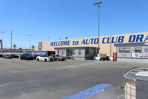 2003 Ford Crown Victoria - Cars park beside the tan 'WELCOME to AUTO CLUB DRA' building with a Lucas Oil banner and red Coca-Cola cooler under a clear sky.