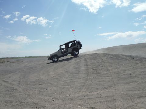 2005 Jeep Wrangler - A Jeep Wrangler navigates a sandy incline under a partly cloudy sky.