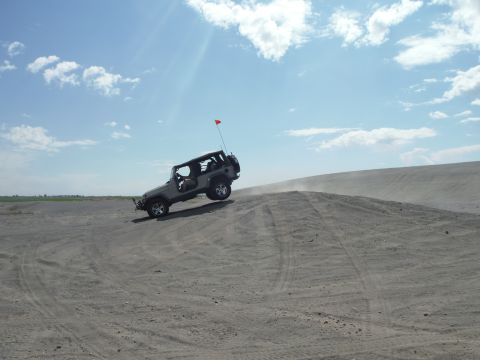 2005 Jeep Wrangler - A Jeep Wrangler navigates a sandy incline under a partly cloudy sky.