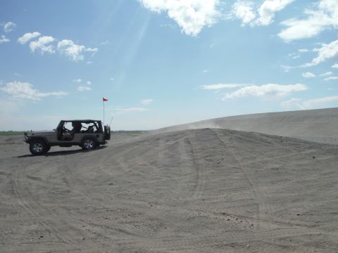 2005 Jeep Wrangler - A tan Jeep Wrangler navigates sandy terrain on a bright, partly cloudy day.