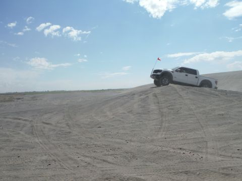 2005 Jeep Wrangler - A white pickup truck navigates a sandy terrain under a bright blue sky with scattered clouds.