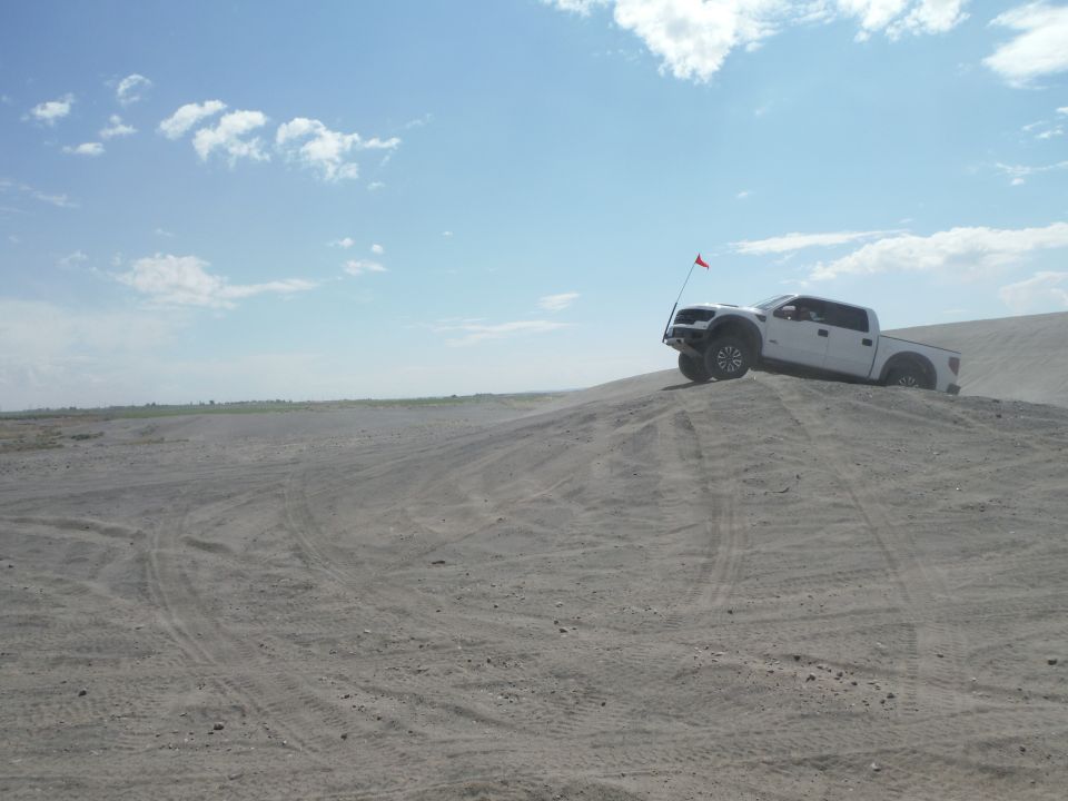 White pickup truck on a sand dune with a red flag