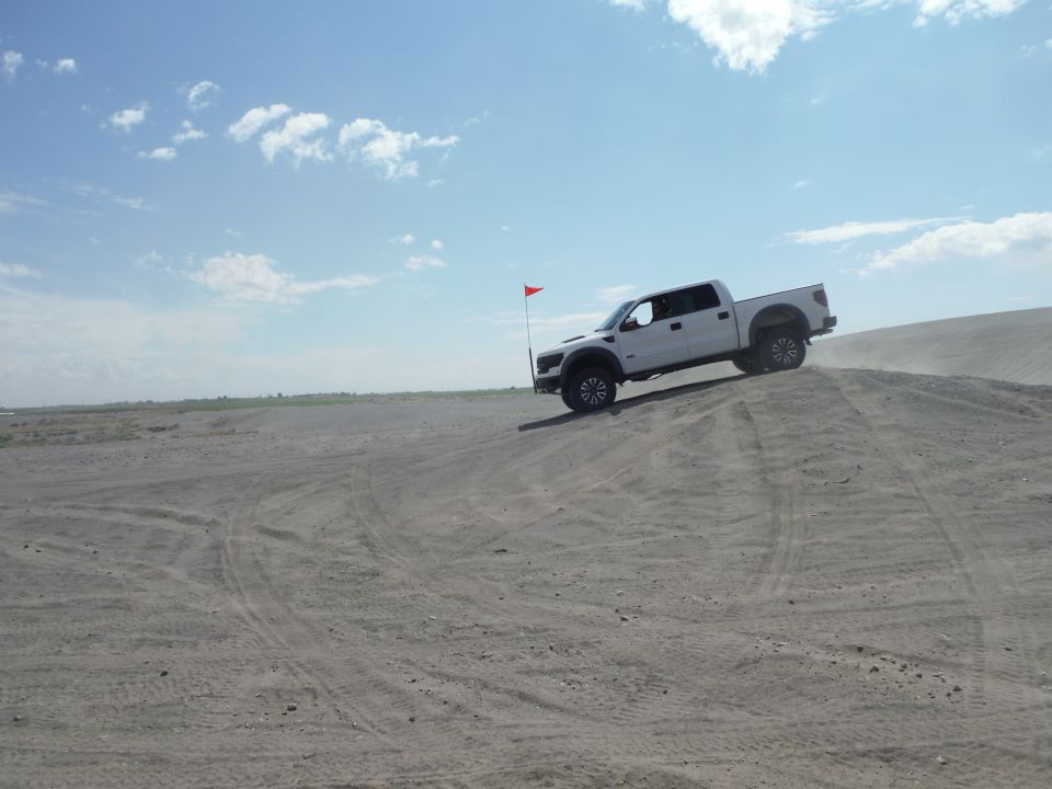 White pickup truck on sand dune, 2010 model year