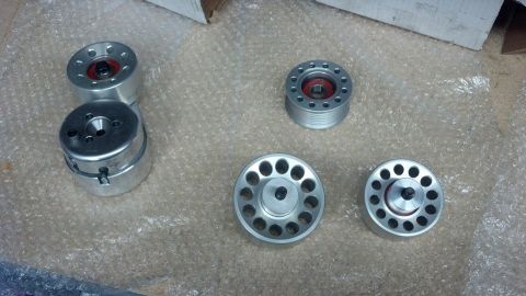 2003 Ford Crown Victoria - Several machined aluminum supercharger pulleys and bearing hubs are arranged on bubble wrap on a workbench.