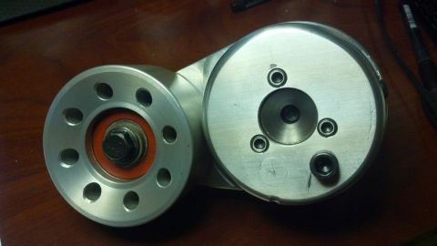 2003 Ford Crown Victoria - multi-hole aluminum pulley with orange seal sits beside a drilled drum housing on a wooden desk.