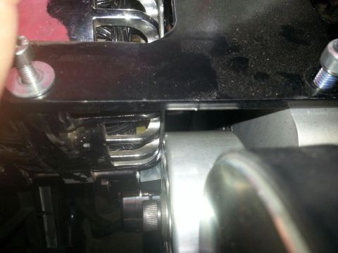 2003 Ford Crown Victoria - tight close-up shows two mounting studs flanking a black painted bracket above polished supercharger surfaces in an engine bay.