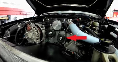 2003 Ford Crown Victoria - open engine bay shows an alternator and black supercharger with a red arrow pointing to a pulley and a light-blue hose.