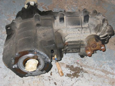 1993 Ford F-150 - A dusty transfer case, likely removed from a vehicle, rests on a stained concrete surface.