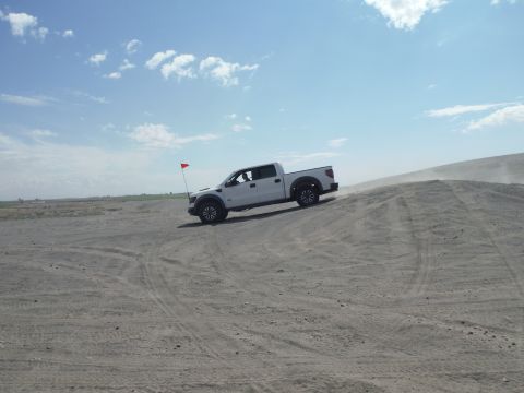 2005 Jeep Wrangler - A white pickup truck navigates a sandy incline on a clear day.