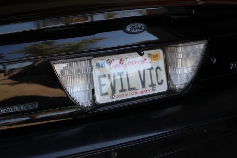 2003 Ford Crown Victoria - Close-up of a black Ford's rear showing a California license plate reading EVIL VIC and an Interceptor emblem.