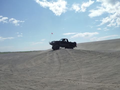 2005 Jeep Wrangler - Pickup truck navigates sandy terrain on a bright, cloudy day.