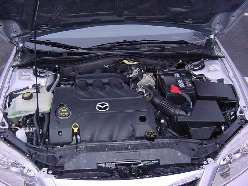 Engine bay of silver Mazda 6 showing black engine cover with Mazda logo, battery, and intake hose