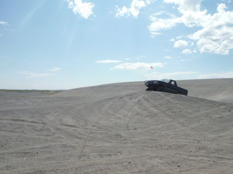 2005 Jeep Wrangler - Pickup truck navigates a sandy terrain on a bright, clear day.
