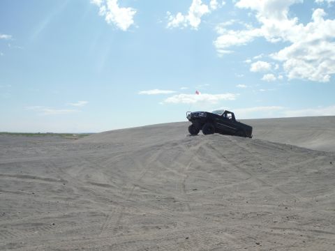 2005 Jeep Wrangler - A black pickup truck is positioned on a sand dune with a flag on its antenna.