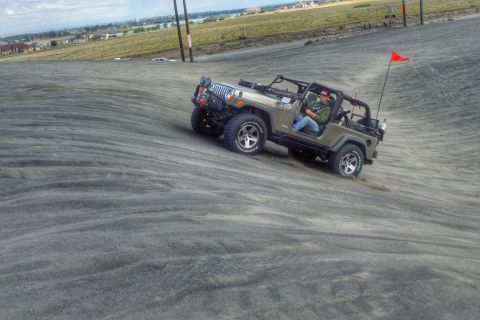 2005 Jeep Wrangler - A Jeep Wrangler navigates a sandy incline, kicking up dust as it ascends.
