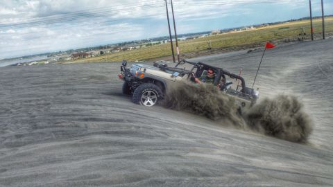 2005 Jeep Wrangler - A Jeep Wrangler navigates a sandy incline, sending a cloud of dust into the air.