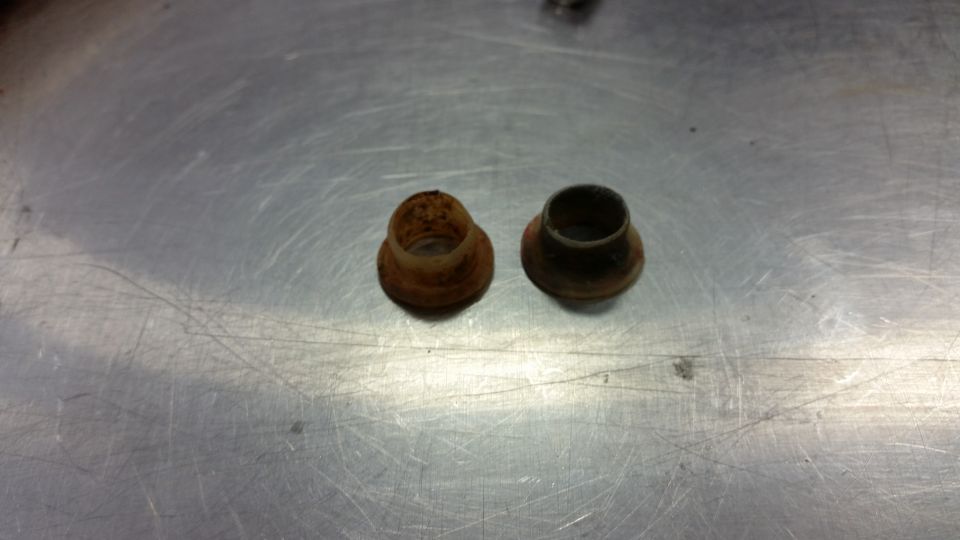 Two rusty metal bushings on a metal surface