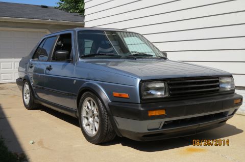 1990 Volkswagen Jetta - A blue 1990 Volkswagen Jetta is shown from a three-quarter front view, parked outside a residence.
