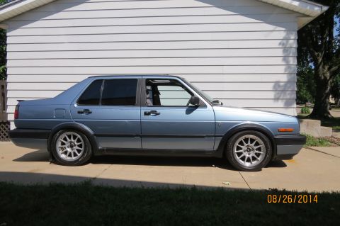 1990 Volkswagen Jetta - Side view of a blue 1990 Volkswagen Jetta sedan with tinted windows and a rear spoiler.