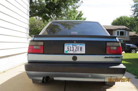 1990 Volkswagen Jetta - Rear view of a 1990 Volkswagen Jetta, showing its taillights and license plate. Another vehicle is parked nearby.