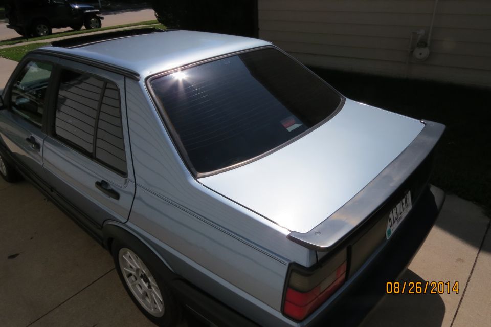Silver sedan with a spoiler and tinted windows. A black Jeep is parked in the background