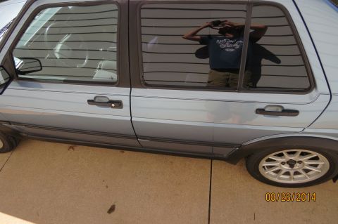 1990 Volkswagen Jetta - A light blue 1990 Volkswagen Jetta is seen from the side, with a reflection of the photographer in the window.