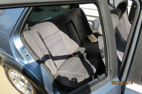 1990 Volkswagen Jetta - The interior rear seats of a blue car are visible, with fabric upholstery and the open door frame.