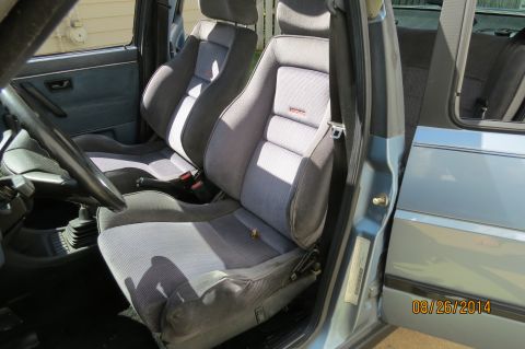1990 Volkswagen Jetta - The interior of a car features grey fabric seats with red Recaro logos visible on the headrests.