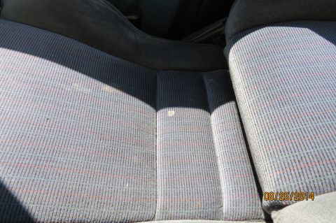 1990 Volkswagen Jetta - The interior of a vehicle shows seats with a patterned fabric, illuminated by sunlight casting shadows.