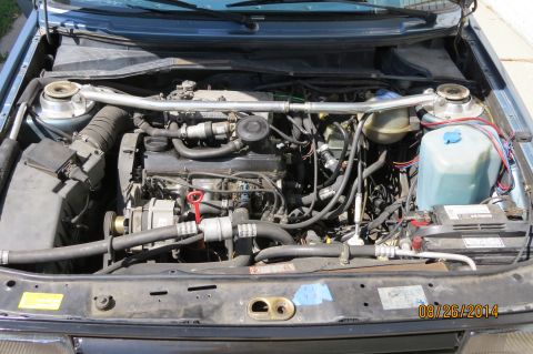 1990 Volkswagen Jetta - Engine bay of a 1990 Volkswagen Jetta, a strut bar and visible battery.