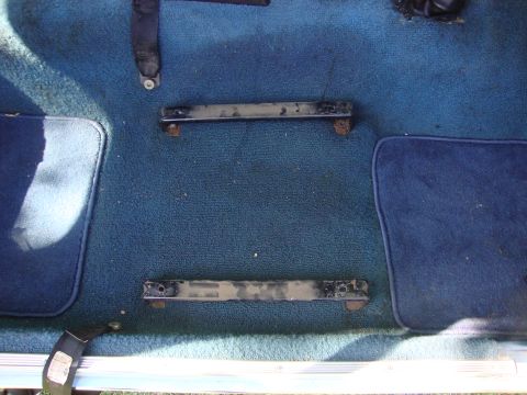1972 Ford Pinto - Car interior floor with blue carpet and visible seat mounting brackets.
