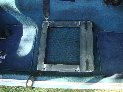 1972 Ford Pinto - Close-up of a seat mounting bracket on the floor of a vehicle, with a seatbelt nearby.