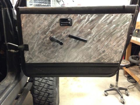 1987 Suzuki Samurai - Interior view of a vehicle door with a custom aluminum panel, manual window crank, and lock knob.