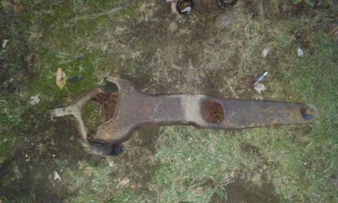 1994 Ford Bronco - This heavily rusted metal part, likely from a vehicle's suspension, lies on the grass with a Supermotors.net watermark.