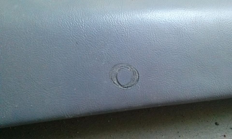 Gray textured interior trim panel with a circular mark, possibly from a removed emblem or button