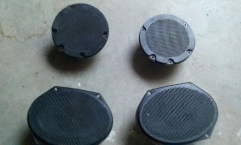 1994 Ford Bronco - Set of four car speakers, including two round and two oval units, displayed on a concrete surface.