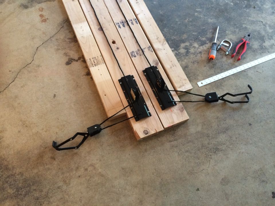 Parts for a bicycle rack laid out on wood planks with tools nearby