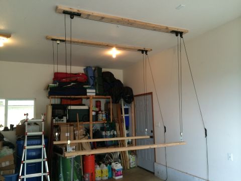 1989 Ford Bronco - A garage ceiling hoist system is installed for storage, with various items stored on shelves and the floor.