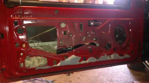 1994 Ford Thunderbird - Interior of a red car door with panels removed, revealing the inner workings.