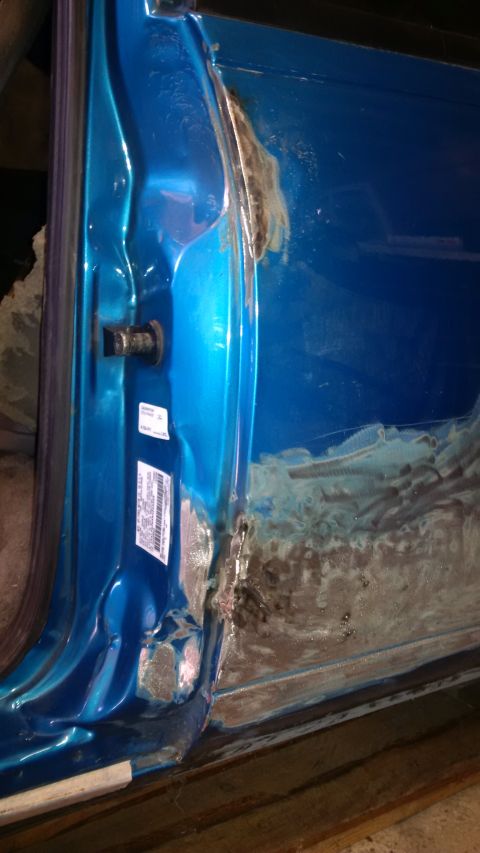 1994 Ford Thunderbird - Close-up of a blue car's interior door frame, revealing significant rust and damage, indicating accident repairs.