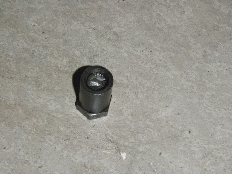 1961 International Scout 800 - A close-up view of a single metal component, likely a fastener or adapter, on a textured floor.