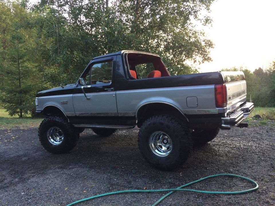 Lifted 1995 Ford Bronco with silver and black paint, red interior, and large off-road tires