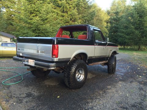 1989 Ford Bronco - Rear view of a lifted 1989 Ford Bronco with off-road tires and two-tone paint.