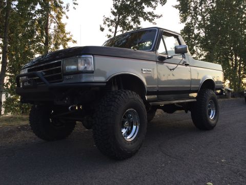 1989 Ford Bronco - This lifted 1989 Ford Bronco features a two-tone paint scheme with a gray body and a black hood.